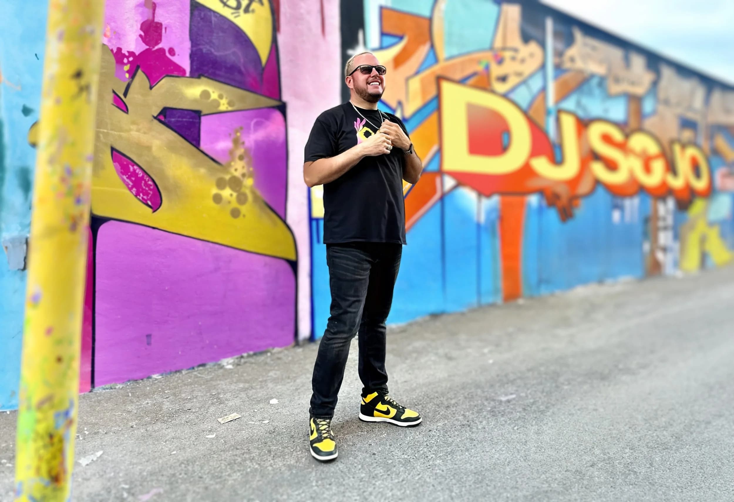 DJ Sojo standing in front of a colorful Los Angeles mural