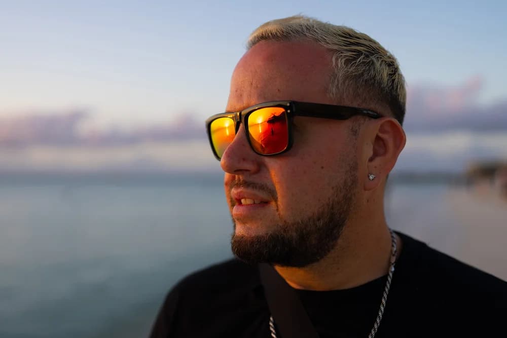 Close portrait of DJ Sojo wearing sunglasses at sunset